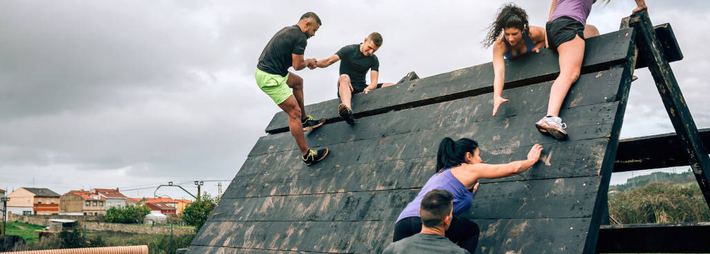 people climbing over an obstacle