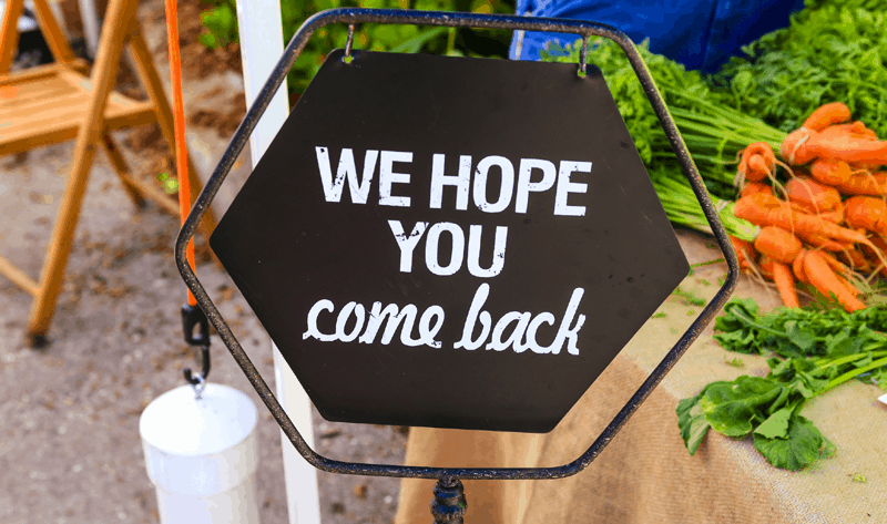 Store owner sign that says 'we hope you come back'.