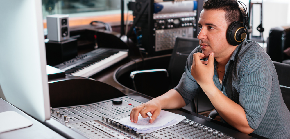 Man sitting at mixing table watching computer screen.