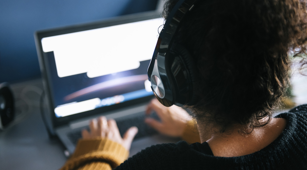 Person with headphones on using computer, listening.