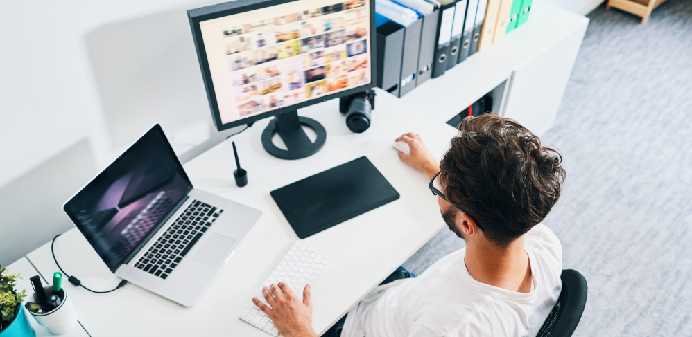 Overhead view of photographer sitting in office editing and managing portfolio